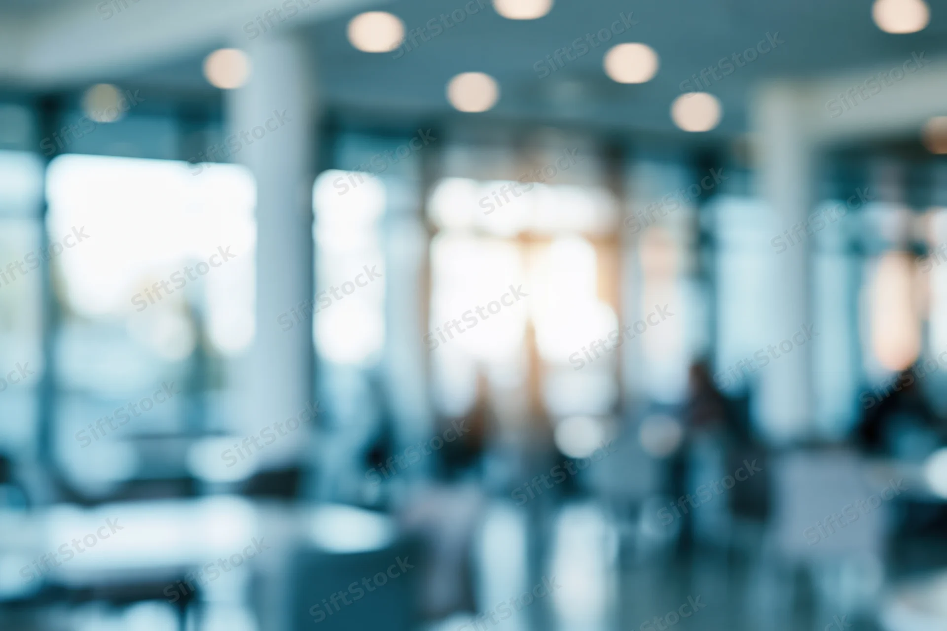 Blurred interior of a modern office lobby with bokeh lights and glass partitions