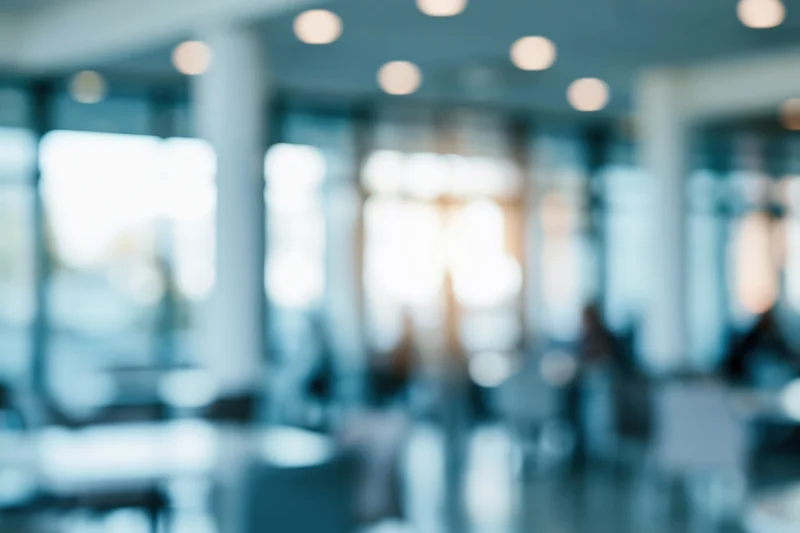 Blurred interior of a modern office lobby with bokeh lights and glass partitions