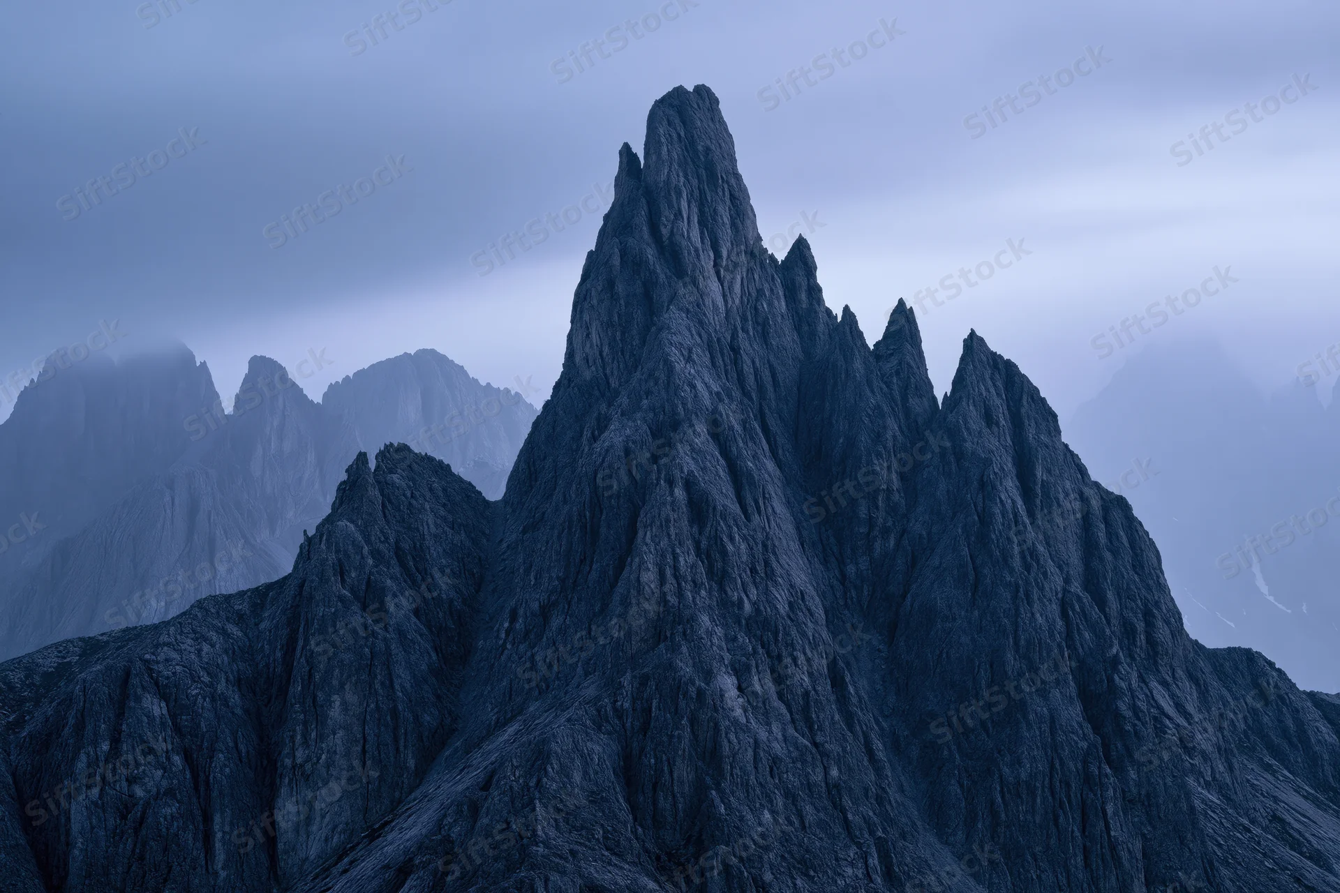 Jagged dolomite mountain peaks rising sharply against a stormy sky