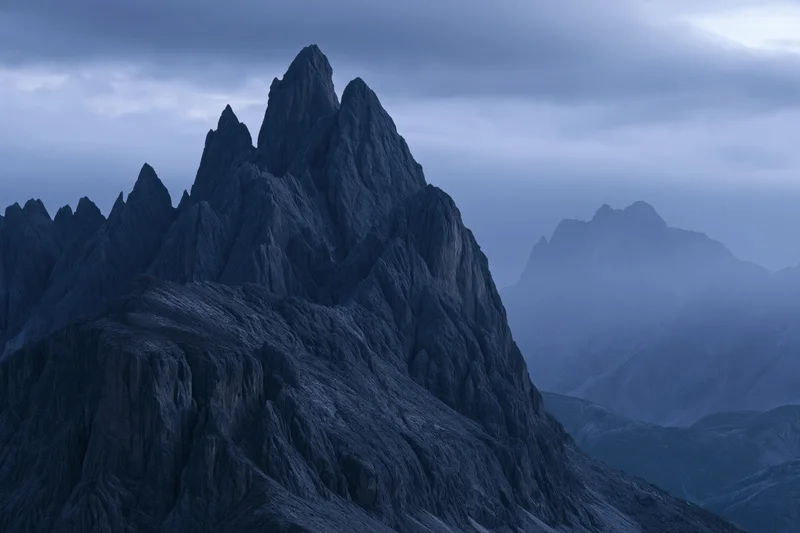 Jagged dolomite mountain peaks rising sharply under stormy overcast sky