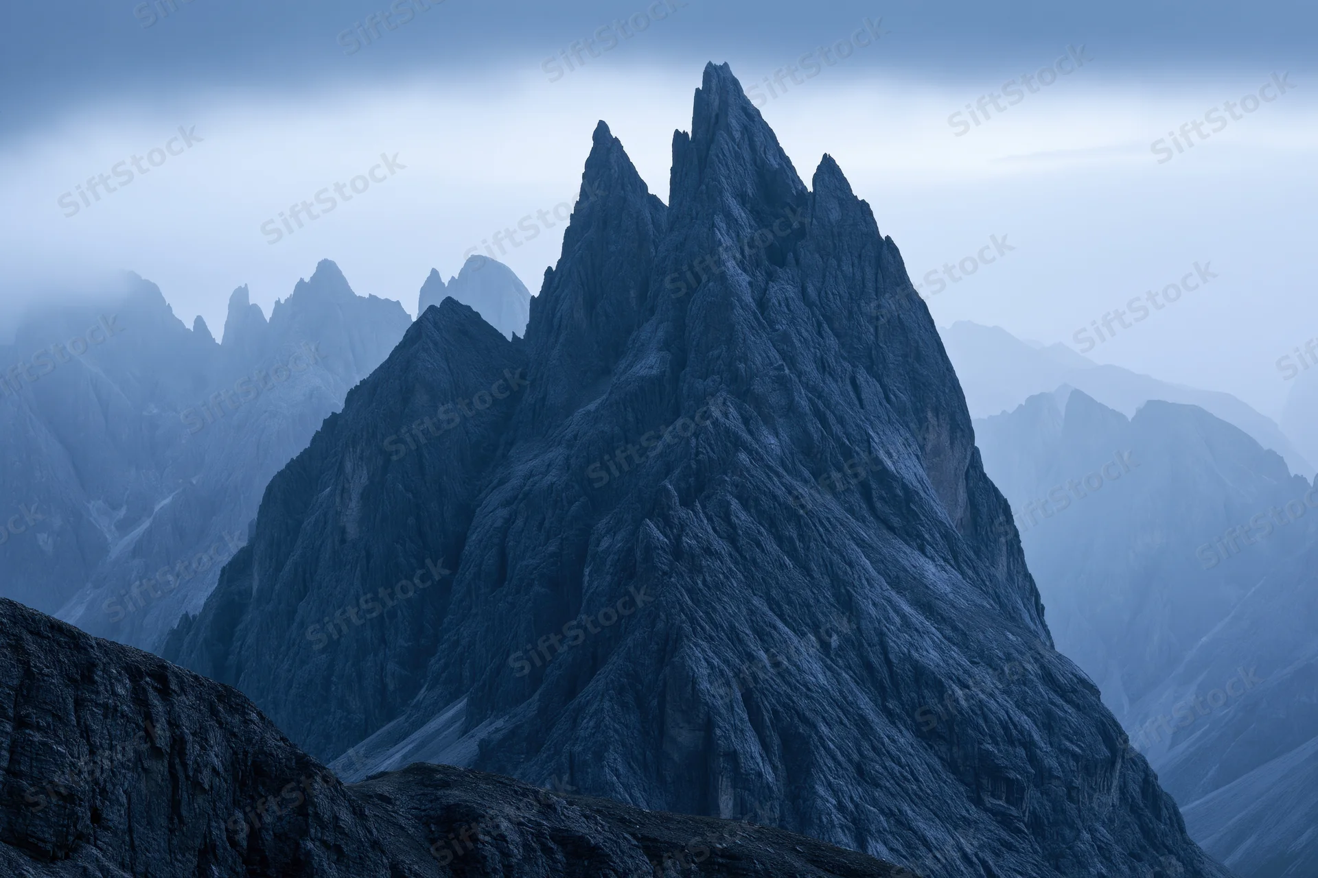 Jagged dolomite mountain peaks rising sharply against a stormy sky
