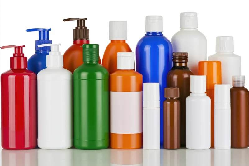 Colorful plastic bottles for personal care products arranged in a row on a reflective white surface