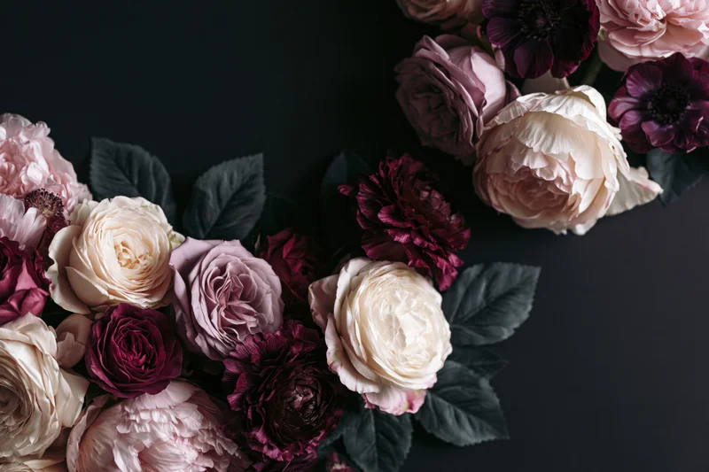 Lush arrangement of peonies, roses and anemones on dark background with copyspace