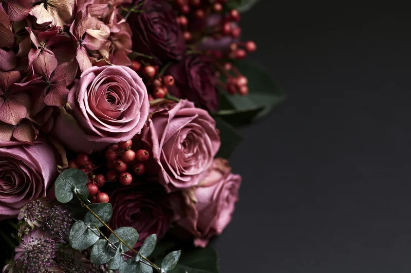 Lush bouquet of dusty pink roses and dried hydrangeas with berries and eucalyptus on dark background