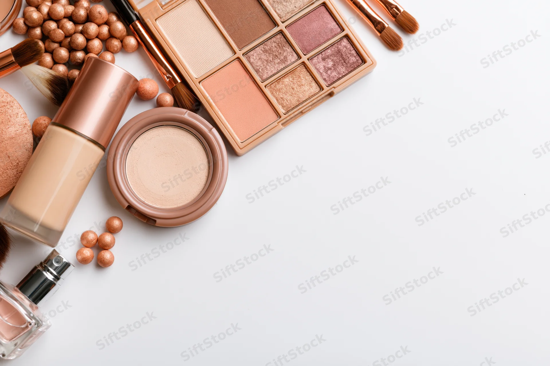 Makeup products arranged in upper-left corner on white surface with copyspace