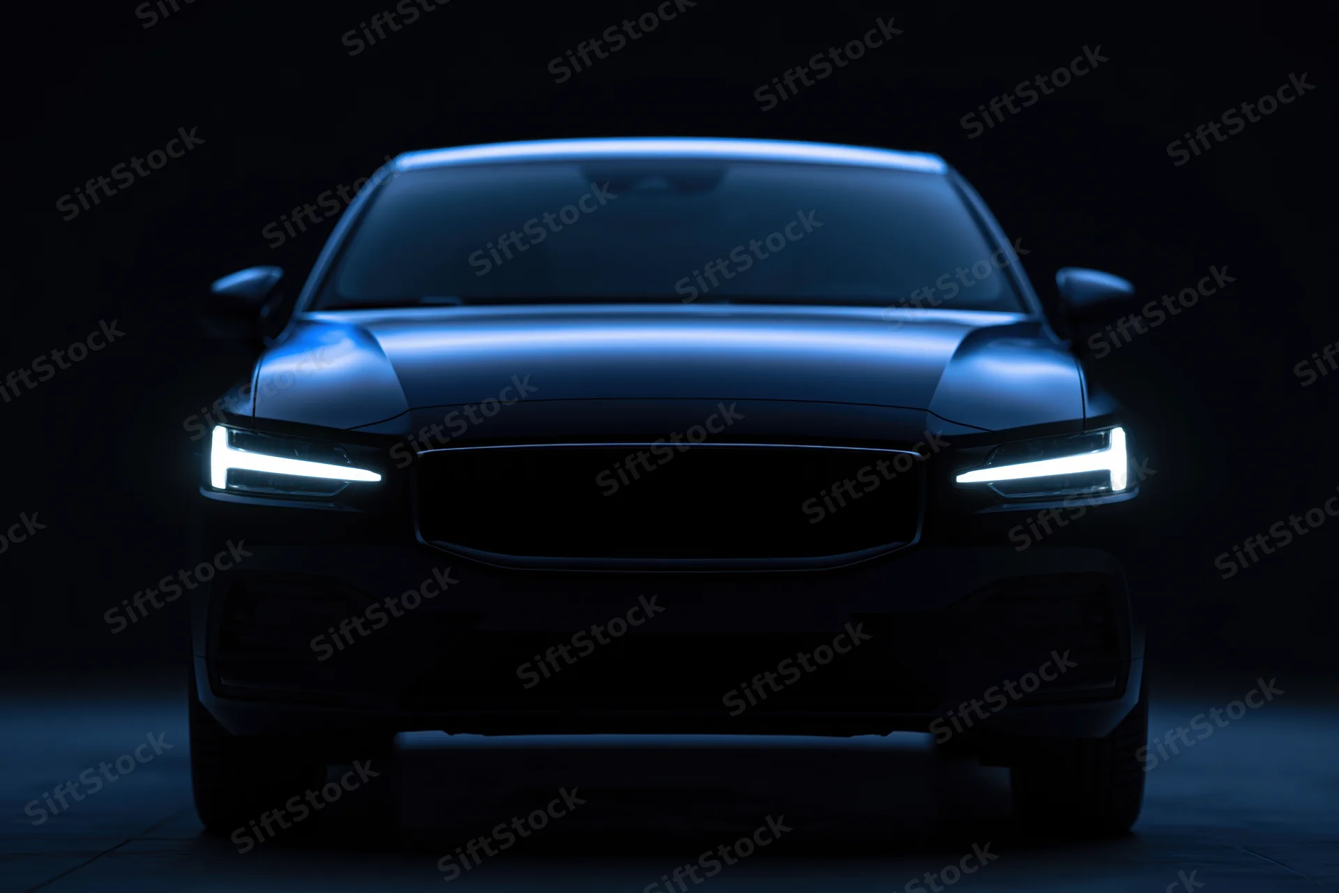 Modern sedan front view in dark studio with illuminated headlights and blue lighting
