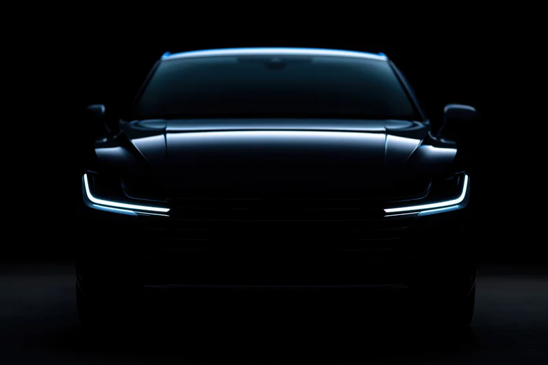 Modern sedan front view in dark studio with illuminated headlights and grille
