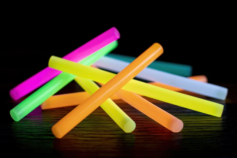 Glowing neon sticks scattered and crossed on a dark wooden surface