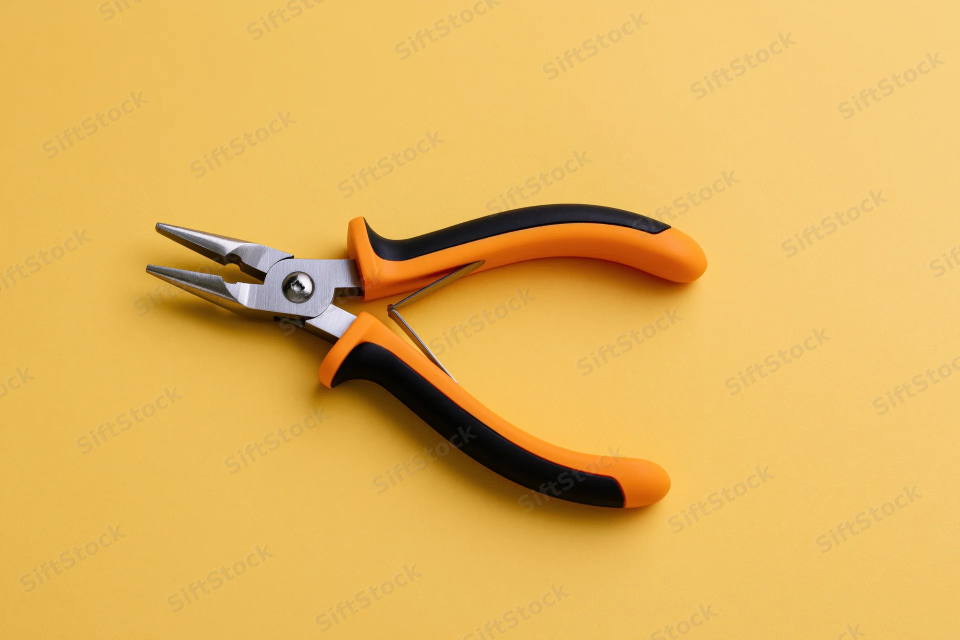 Needle-nose pliers lying open on a flat yellow background