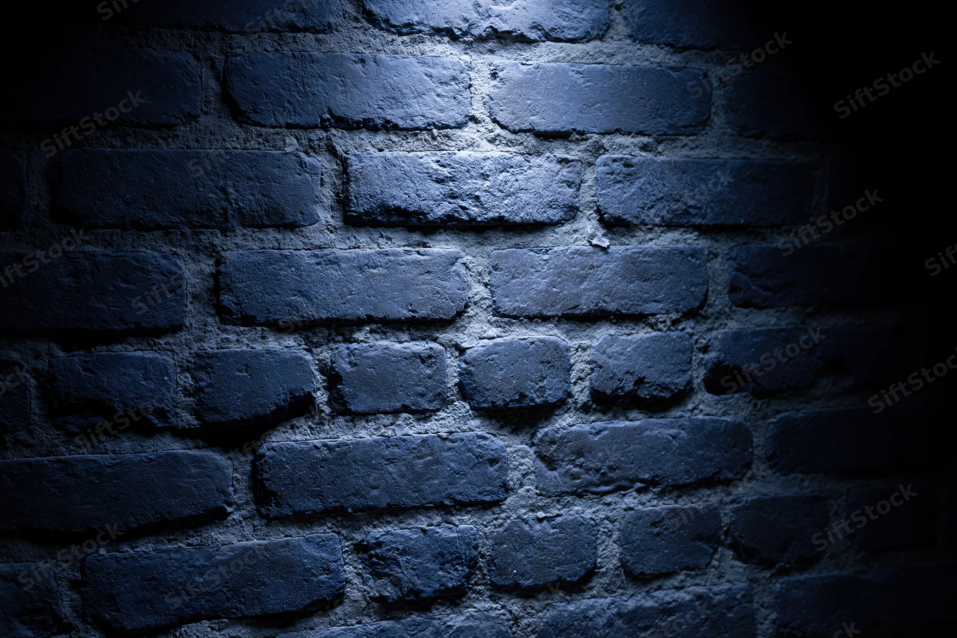 Old brick wall surface lit by spotlight in dark interior