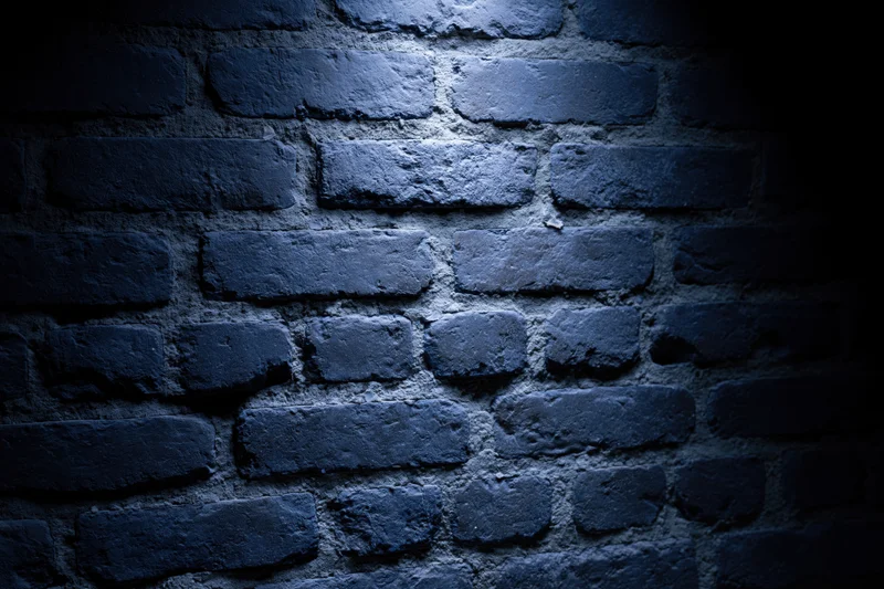 Old brick wall surface lit by spotlight in dark interior