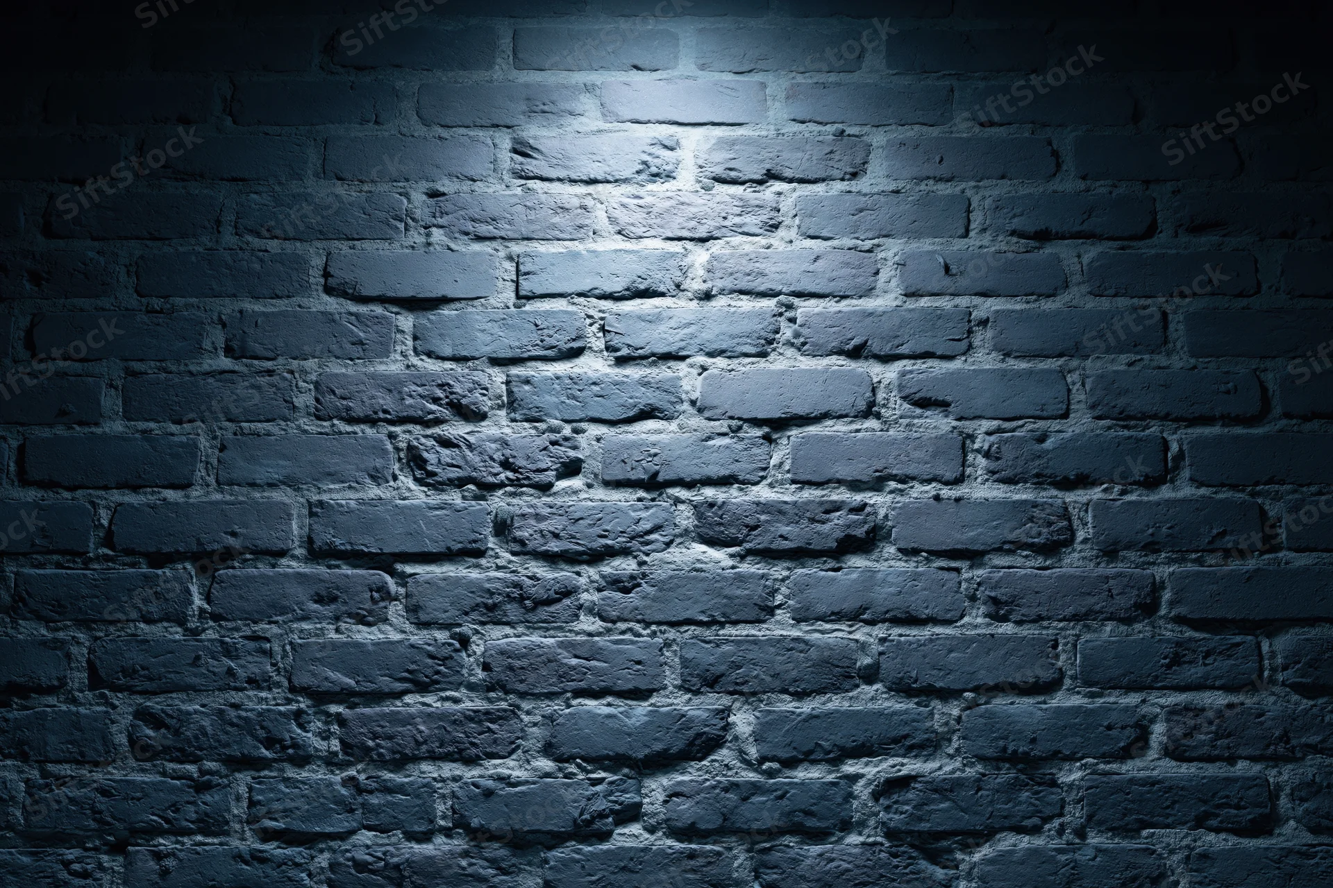 Old brick wall surface illuminated by spotlight in dark interior