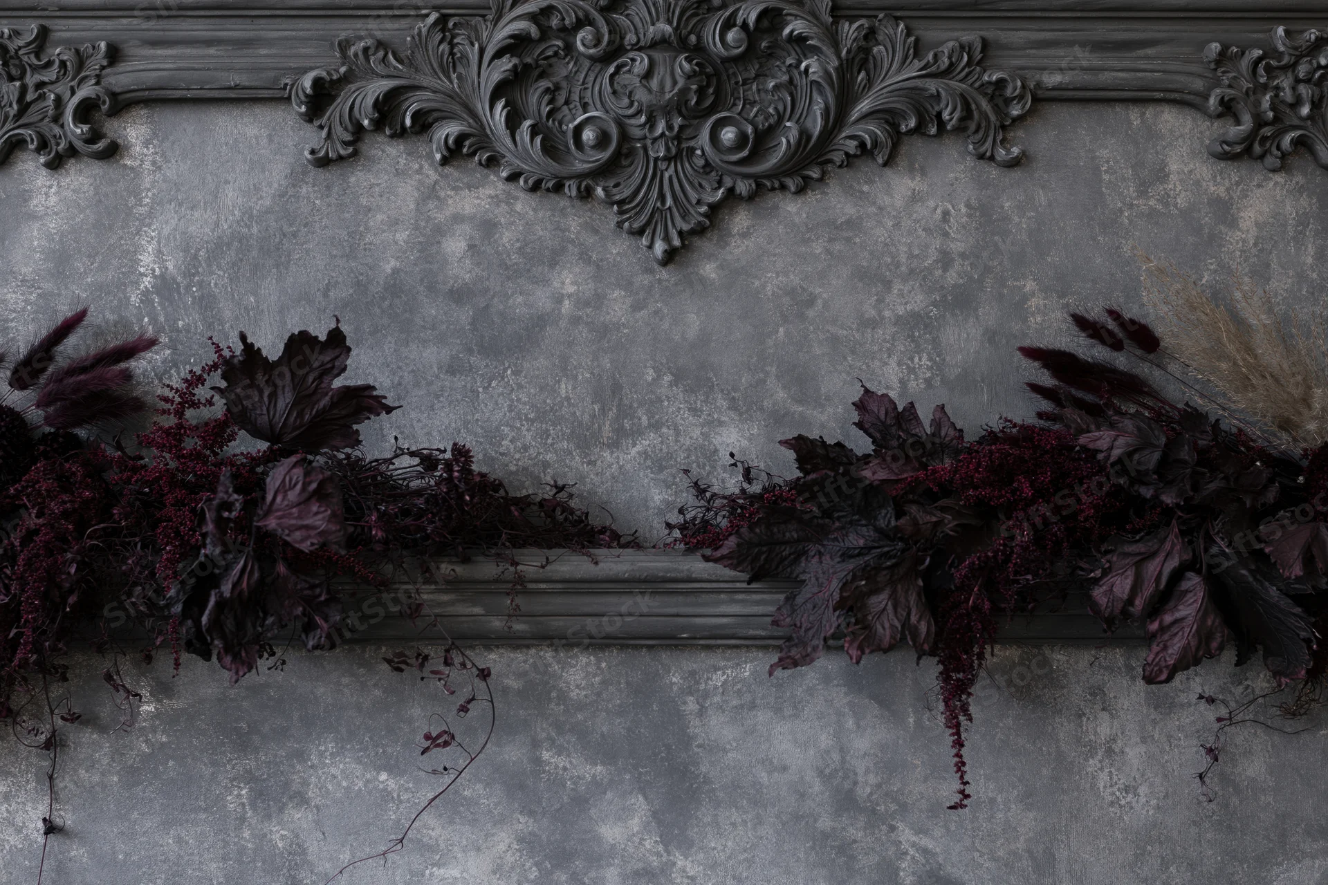 Ornate baroque plaster wall panel with dark dried botanical garland arrangement
