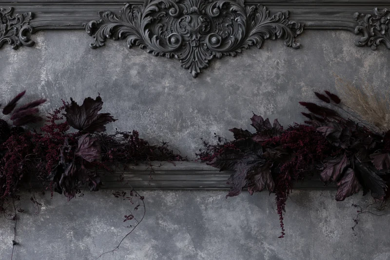 Ornate baroque plaster wall panel with dark dried botanical garland arrangement