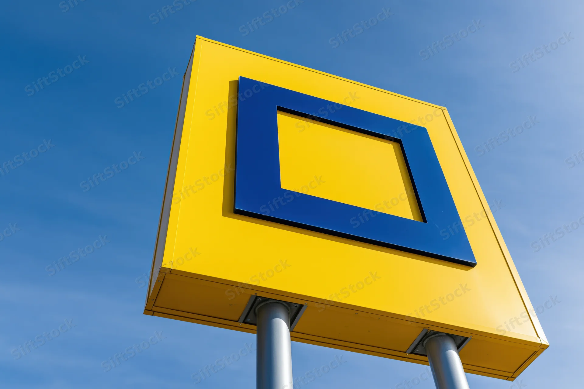 Yellow pylon sign with blue square logo against clear blue sky