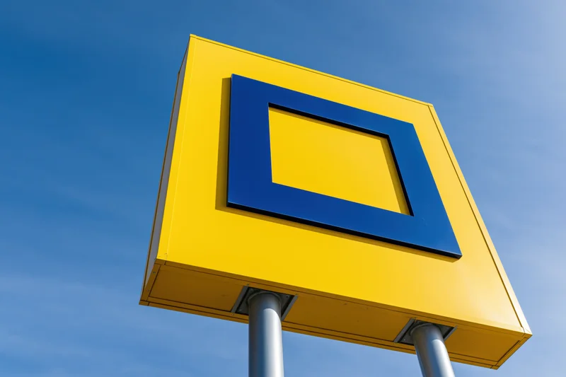 Yellow pylon sign with blue square logo against clear blue sky