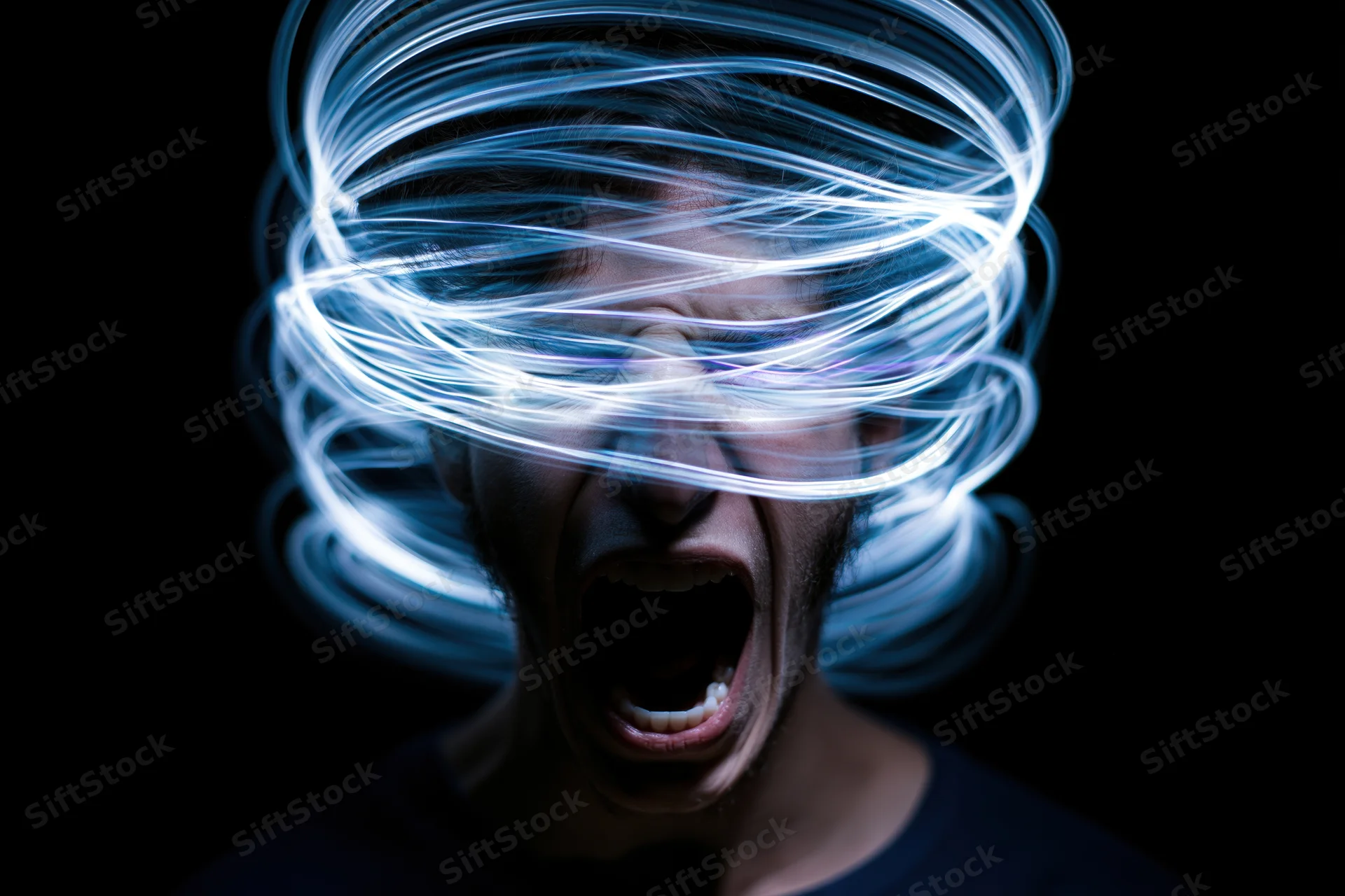 Man screaming with swirling blue light around his head against dark background