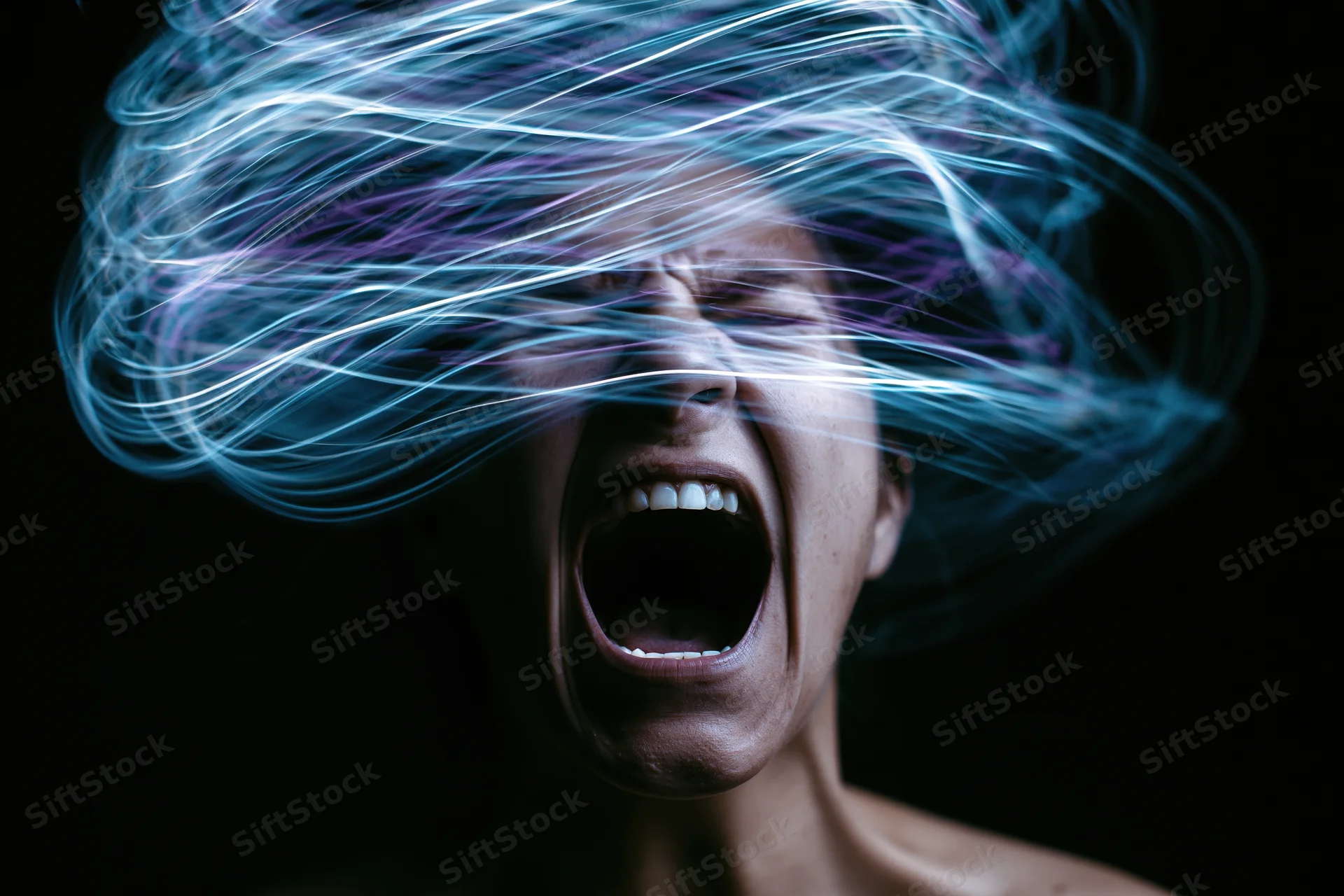 Woman screaming with swirling light trails around her face against dark background