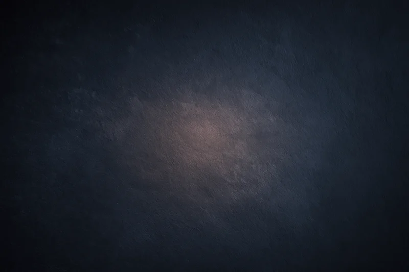 Dark textured surface with soft gradient lighting centered in the frame