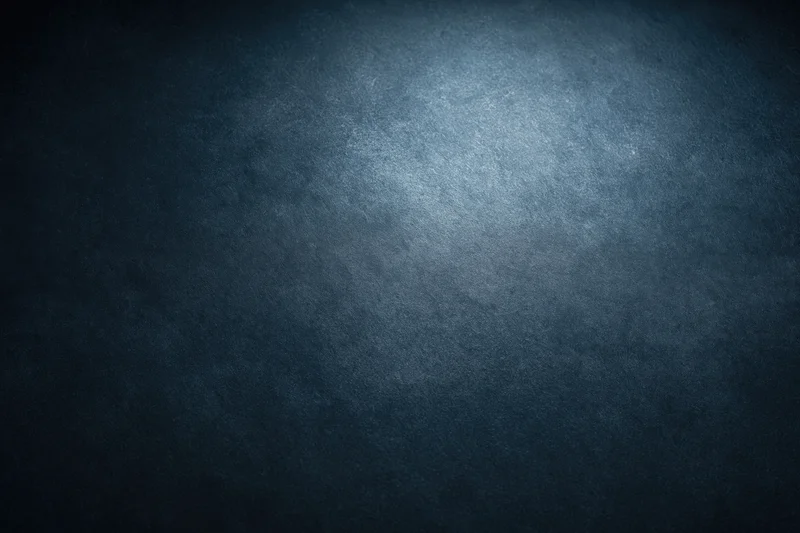 Dark textured surface with soft gradient lighting and spotlight effect