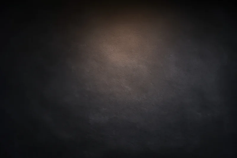 Dark textured surface with soft gradient lighting centered in the frame