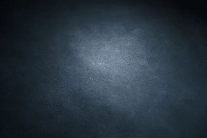 Dark charcoal textured studio backdrop with centered spotlight and vignette effect