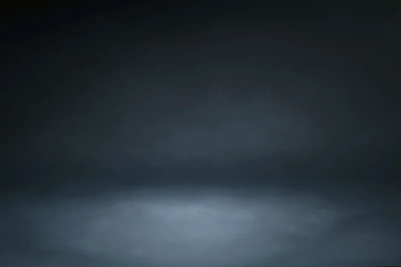 Dark charcoal studio backdrop with centered spotlight and gradient lighting