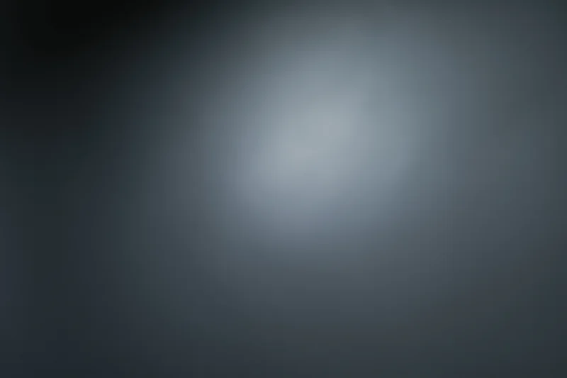 Smooth dark grey gradient background with soft light centered and subtle vignette effect