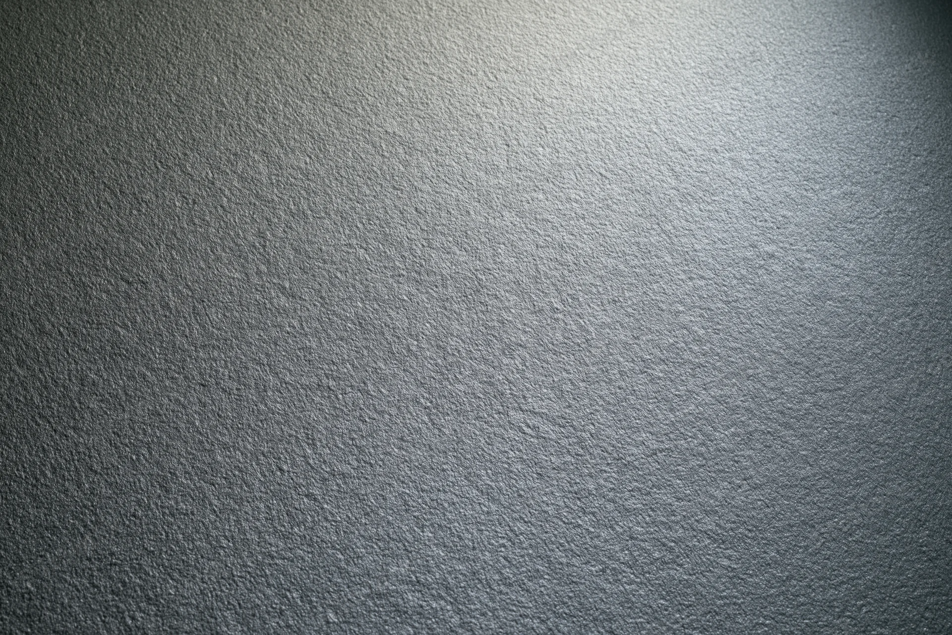 Textured grey surface filling the frame with soft lighting gradient