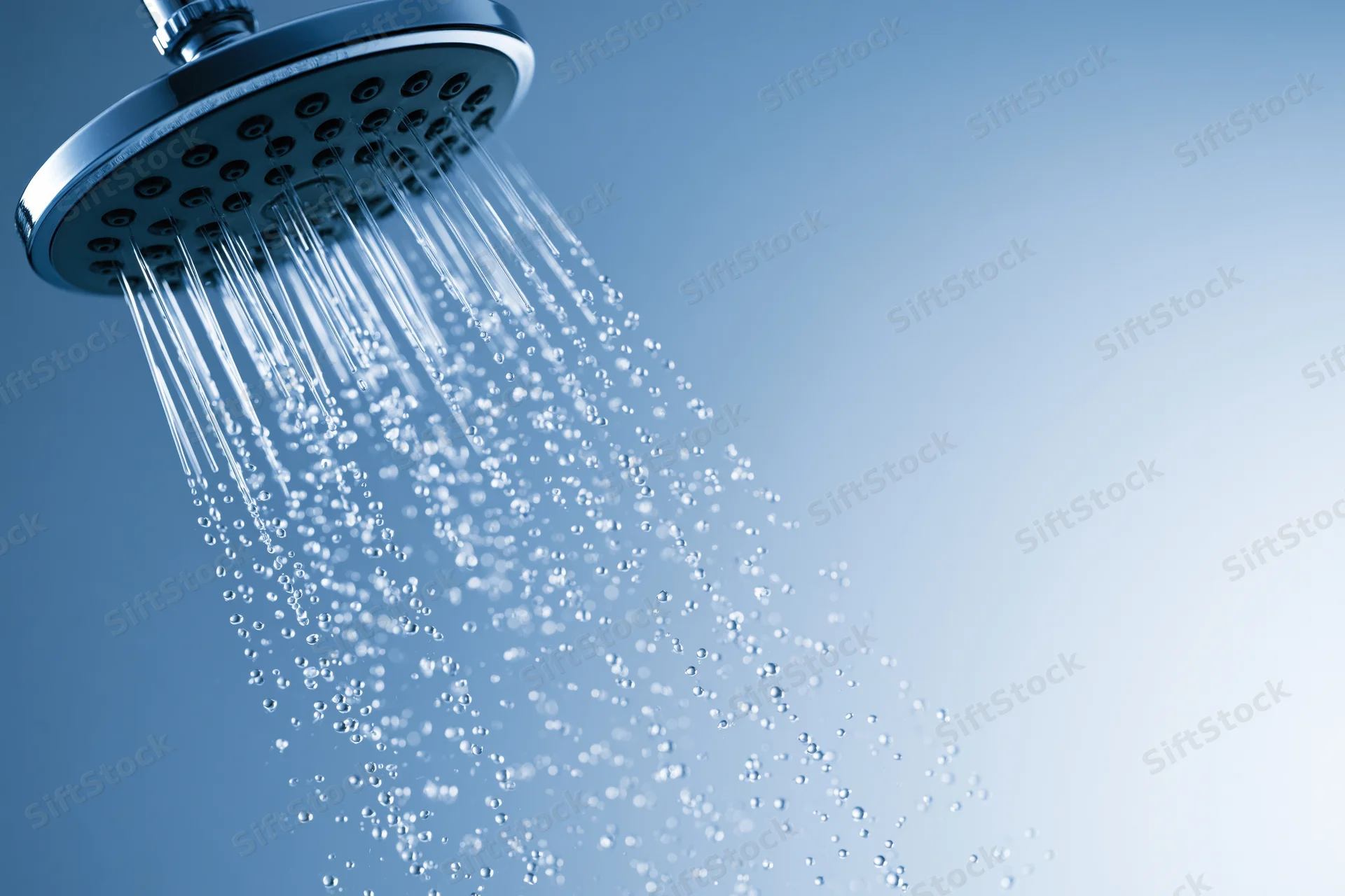 Chrome shower head spraying water droplets against a blue gradient background