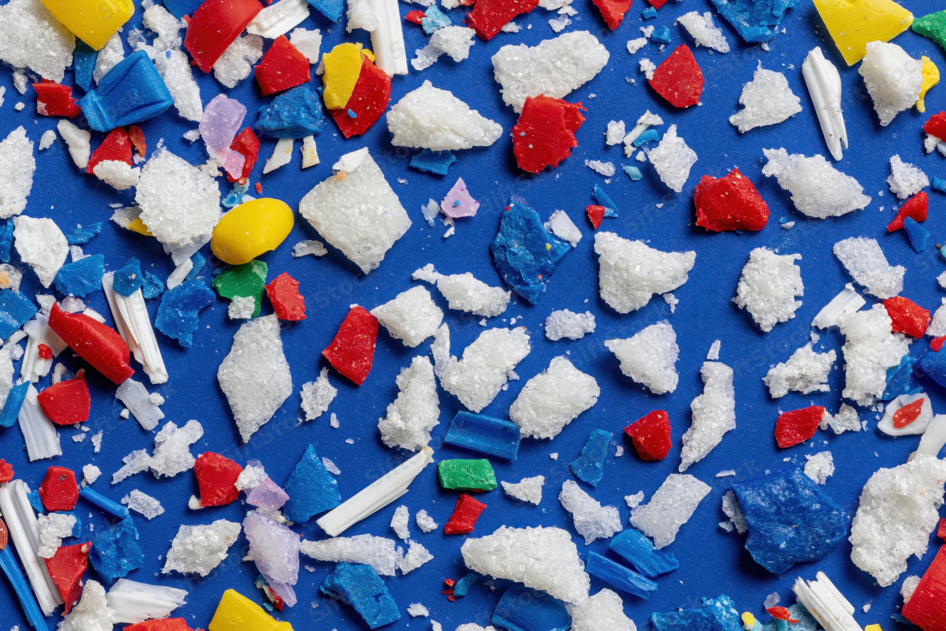 Scattered fragments of colorful plastic debris on a blue surface