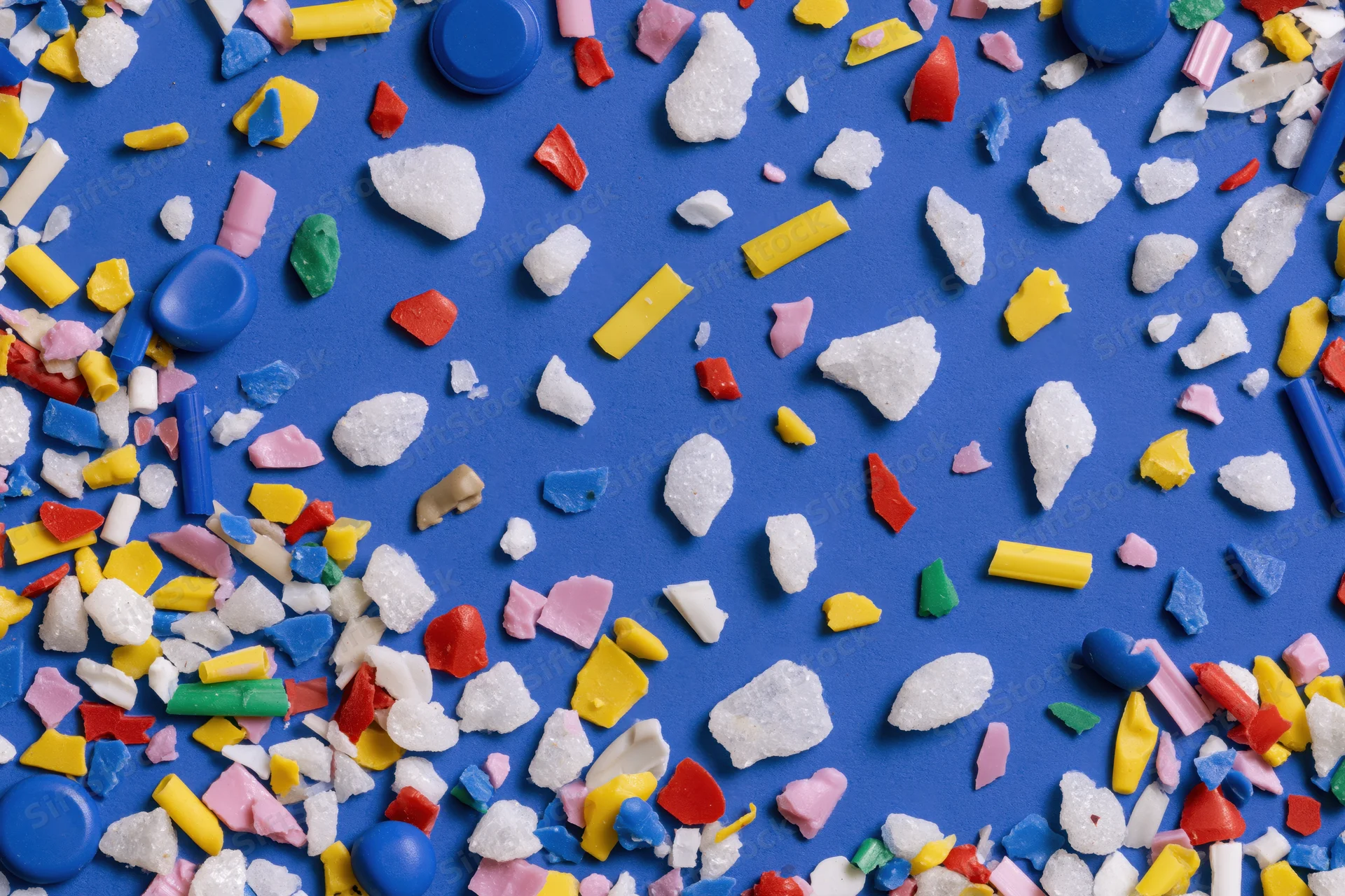 Scattered colorful plastic fragments and microplastic debris on blue background