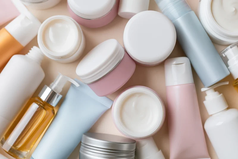 Scattered skincare and cosmetic containers in pastel tones on a flat surface