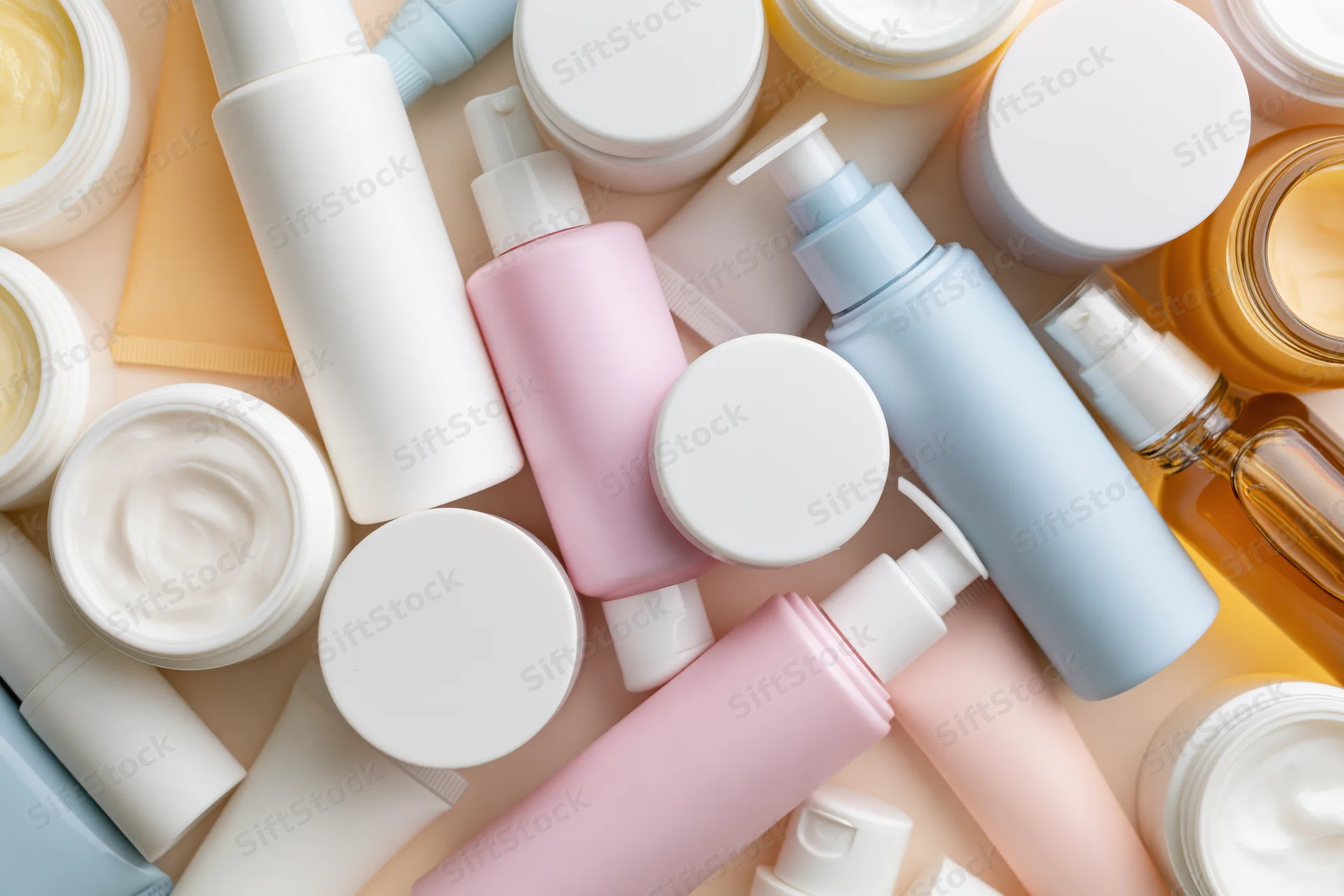 Scattered skincare and cosmetic containers in pastel colors on a flat surface