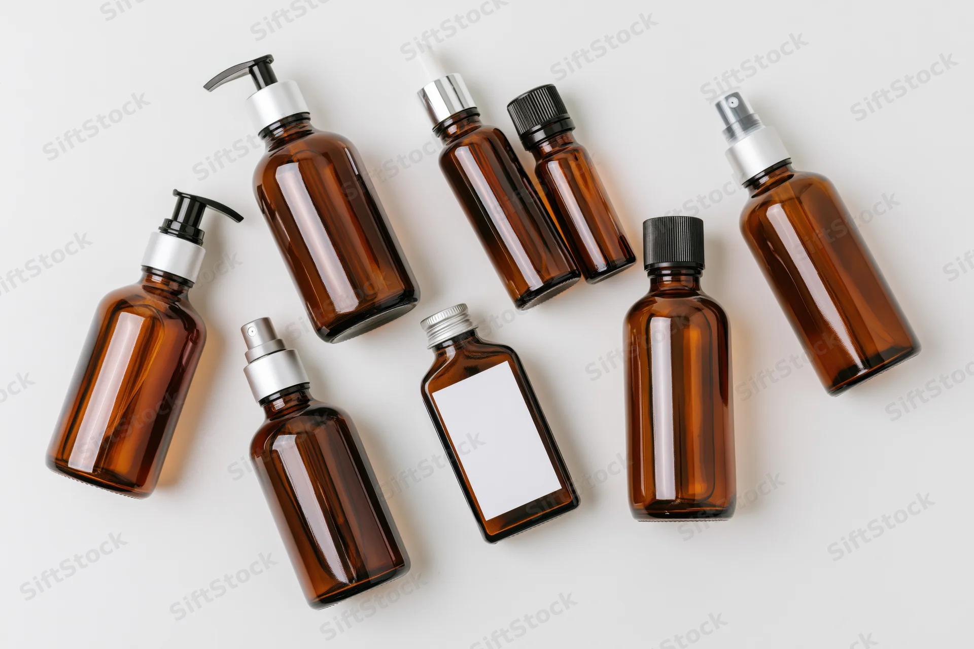 Amber glass bottles with various dispensers arranged on white background