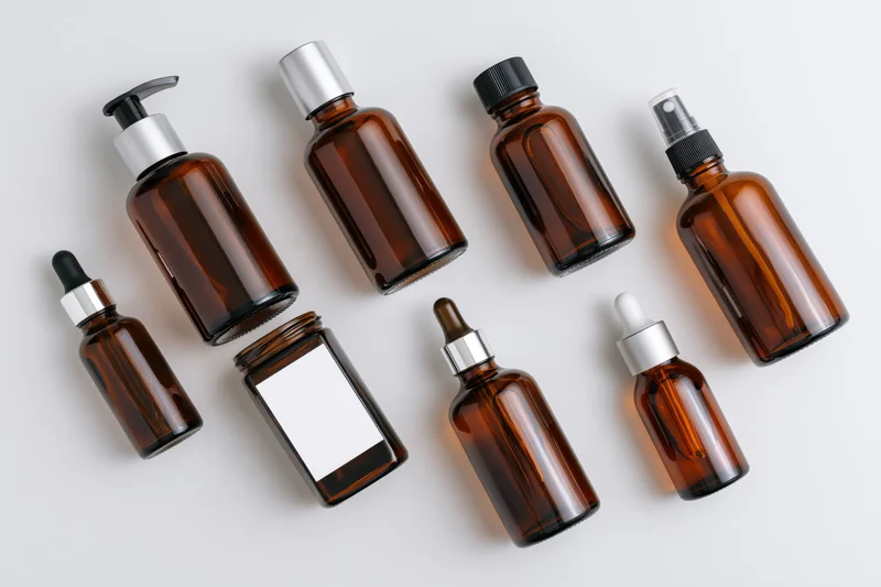 Amber glass bottles with various dispensers arranged on white surface