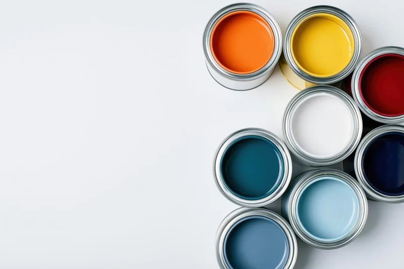 Open paint cans arranged in a diagonal cluster on a white surface with copyspace