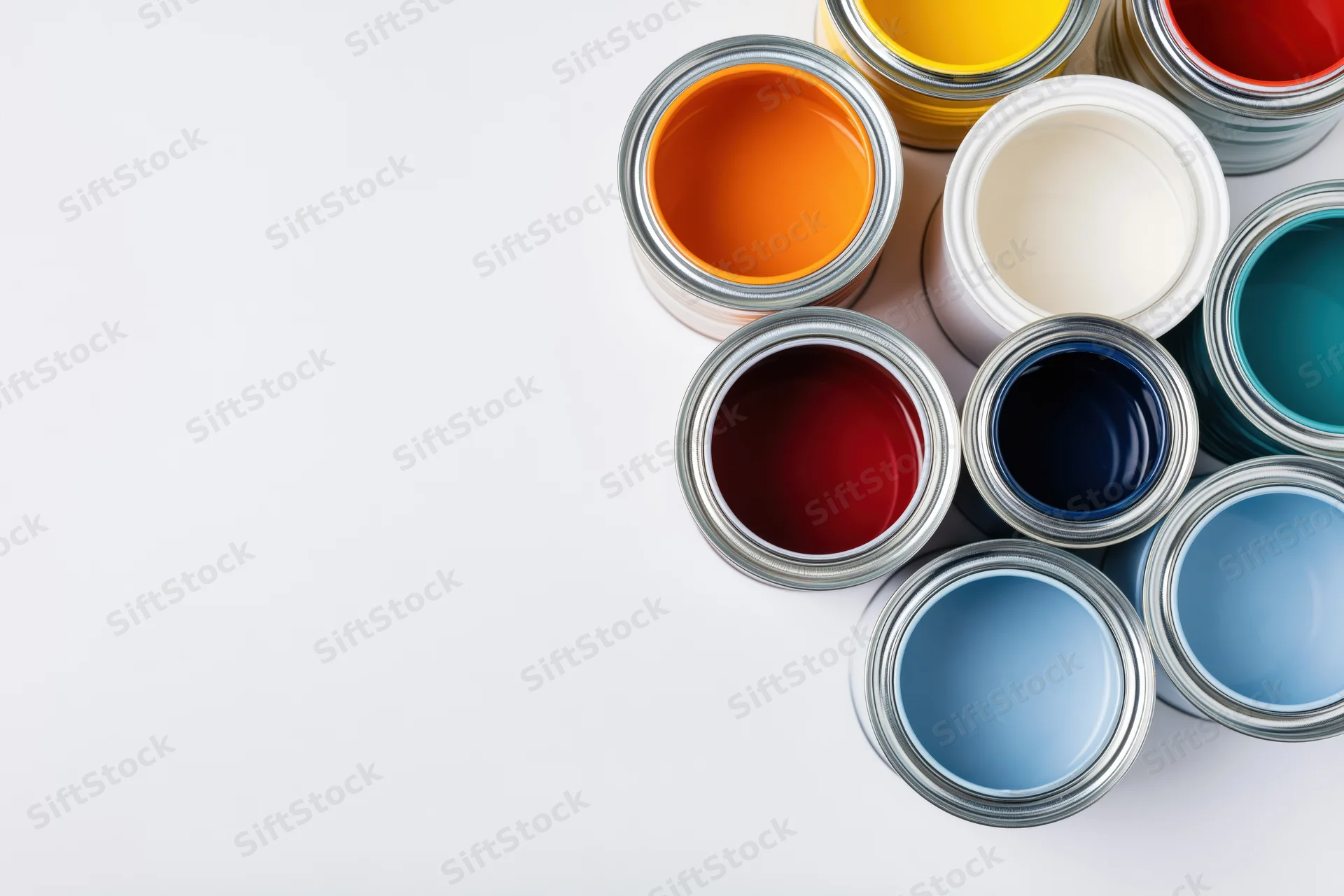 Open paint cans arranged in a diagonal cluster on a white surface with copyspace