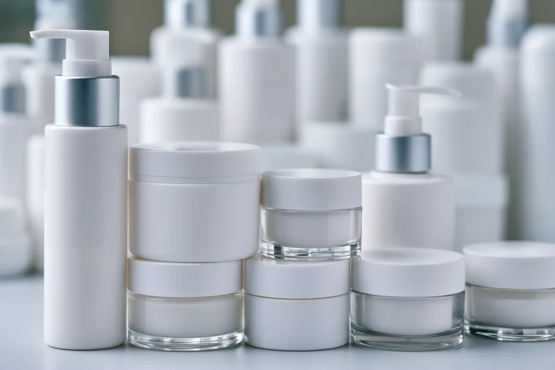 White unlabeled skincare jars and pump bottles arranged on a clean surface with copyspace
