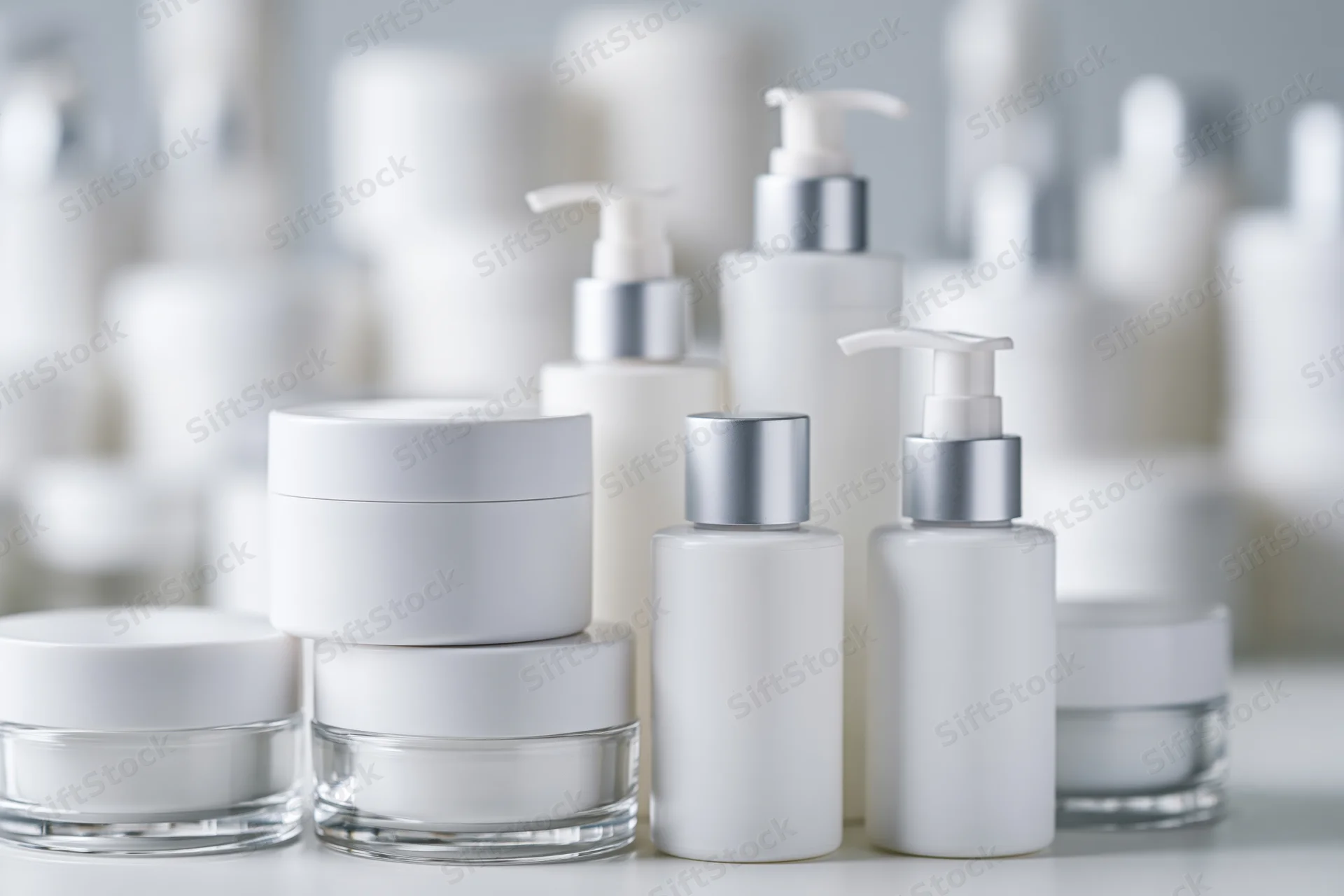 White unlabeled skincare jars and pump bottles arranged on a surface