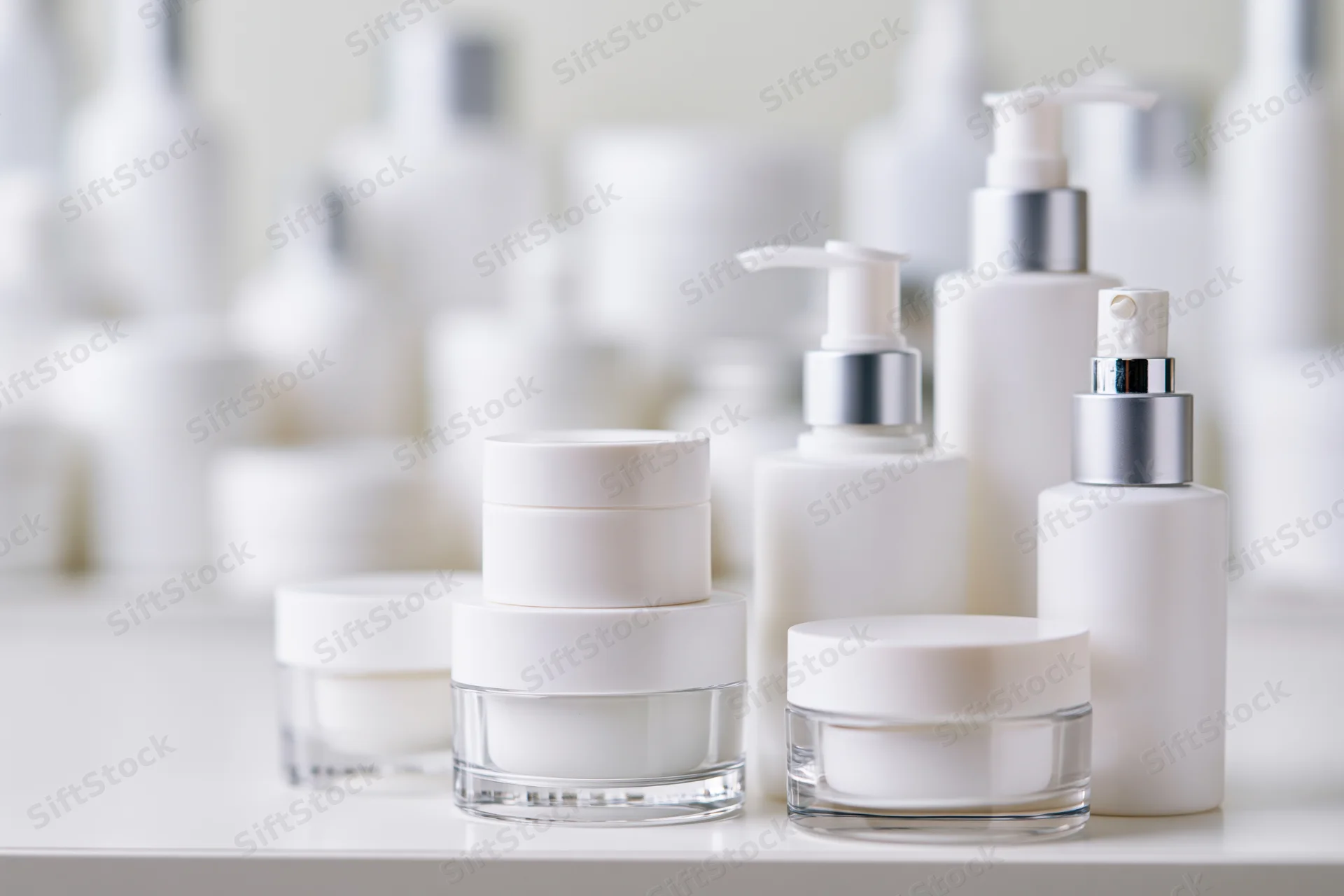White unlabeled skincare jars and pump bottles arranged on a shelf in a studio setting