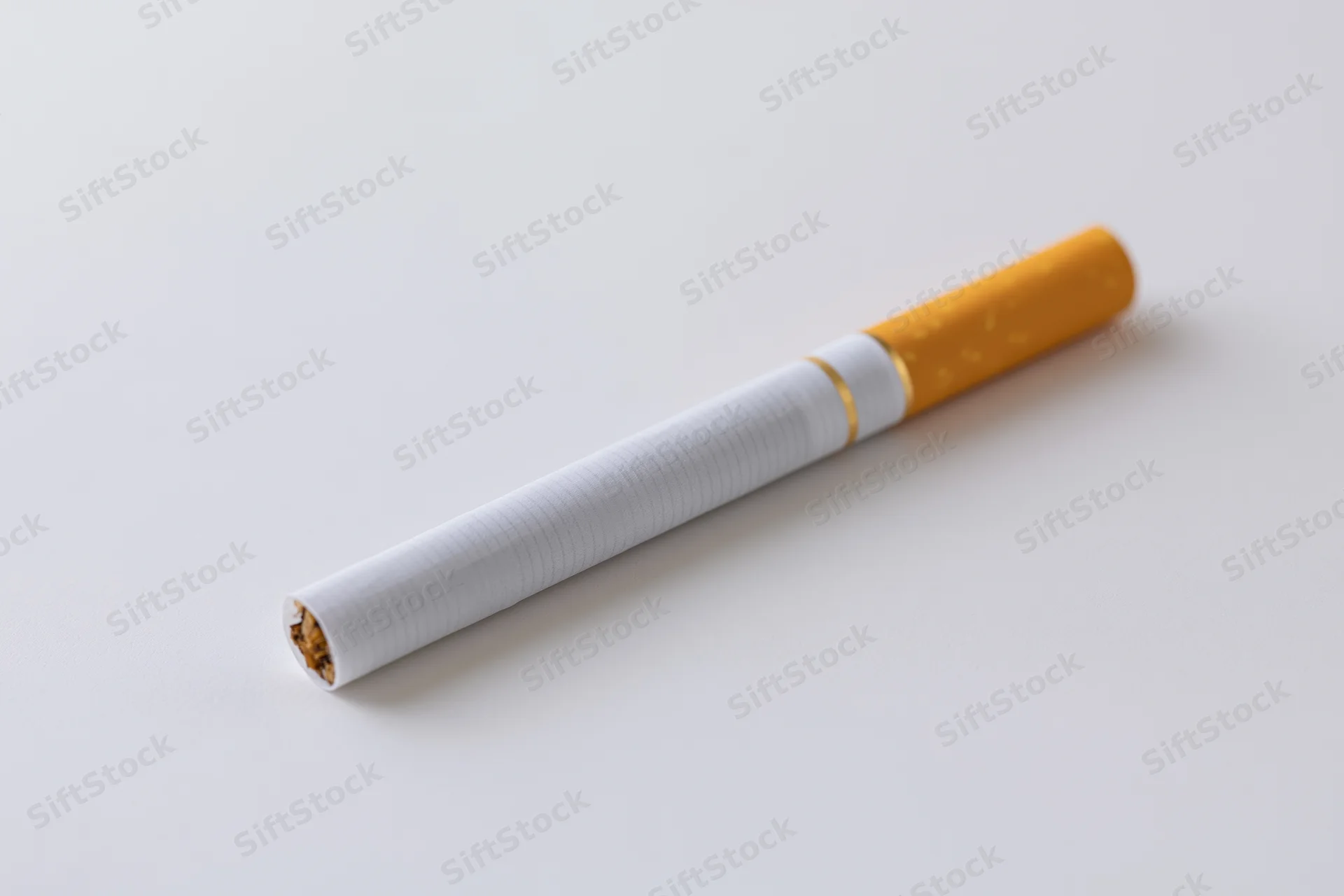 Unlit cigarette lying diagonally on a white surface