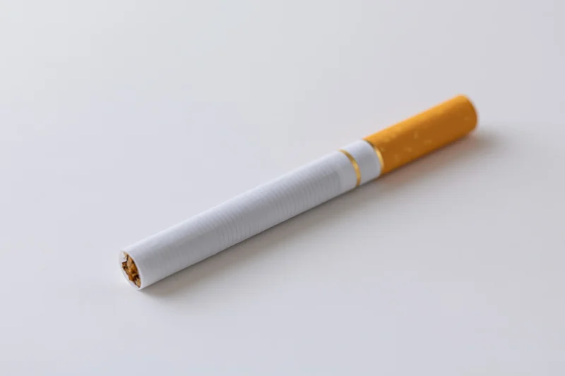Unlit cigarette lying diagonally on a white surface