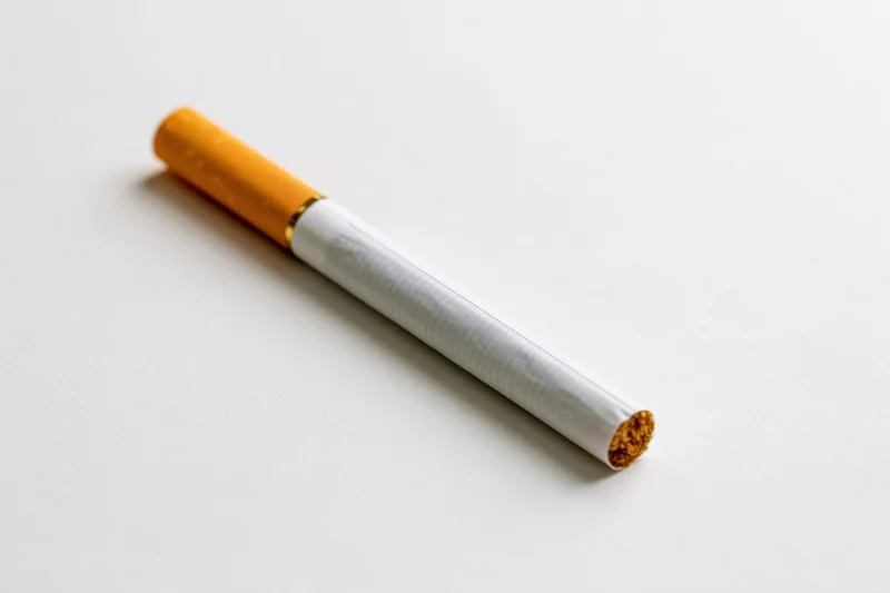Unlit cigarette lying diagonally on a white surface