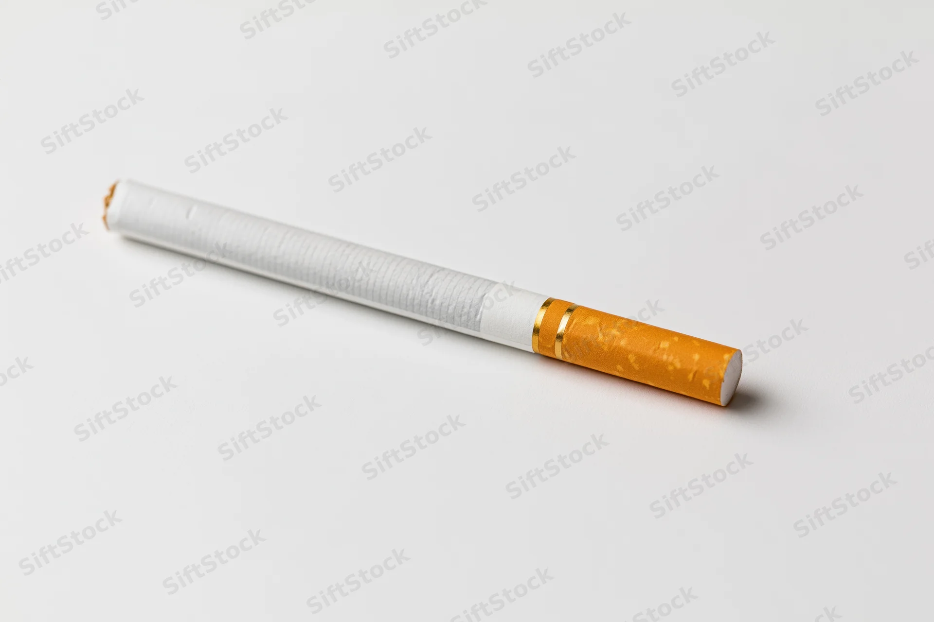 Unlit cigarette lying diagonally on a white surface