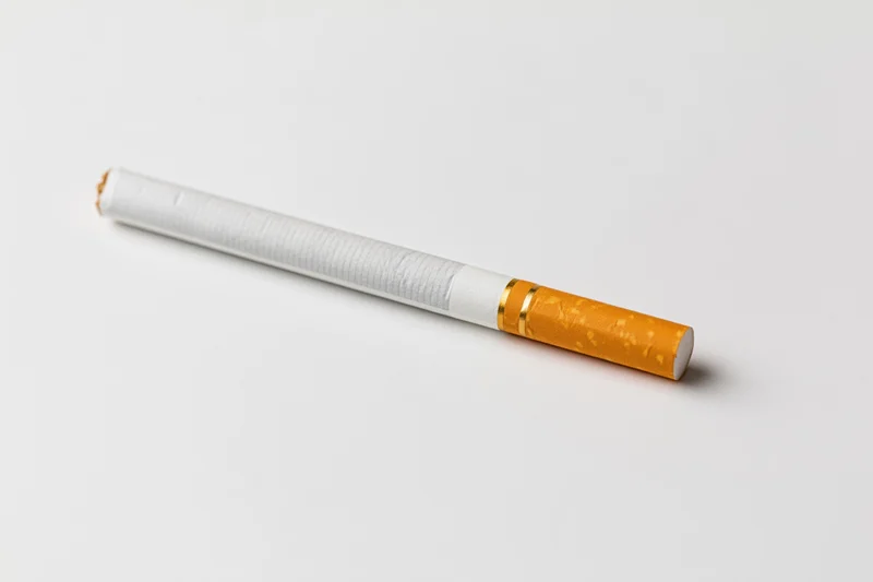 Unlit cigarette lying diagonally on a white surface