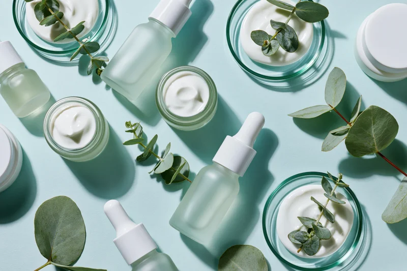 Skincare products and eucalyptus leaves arranged in flat lay on mint blue surface