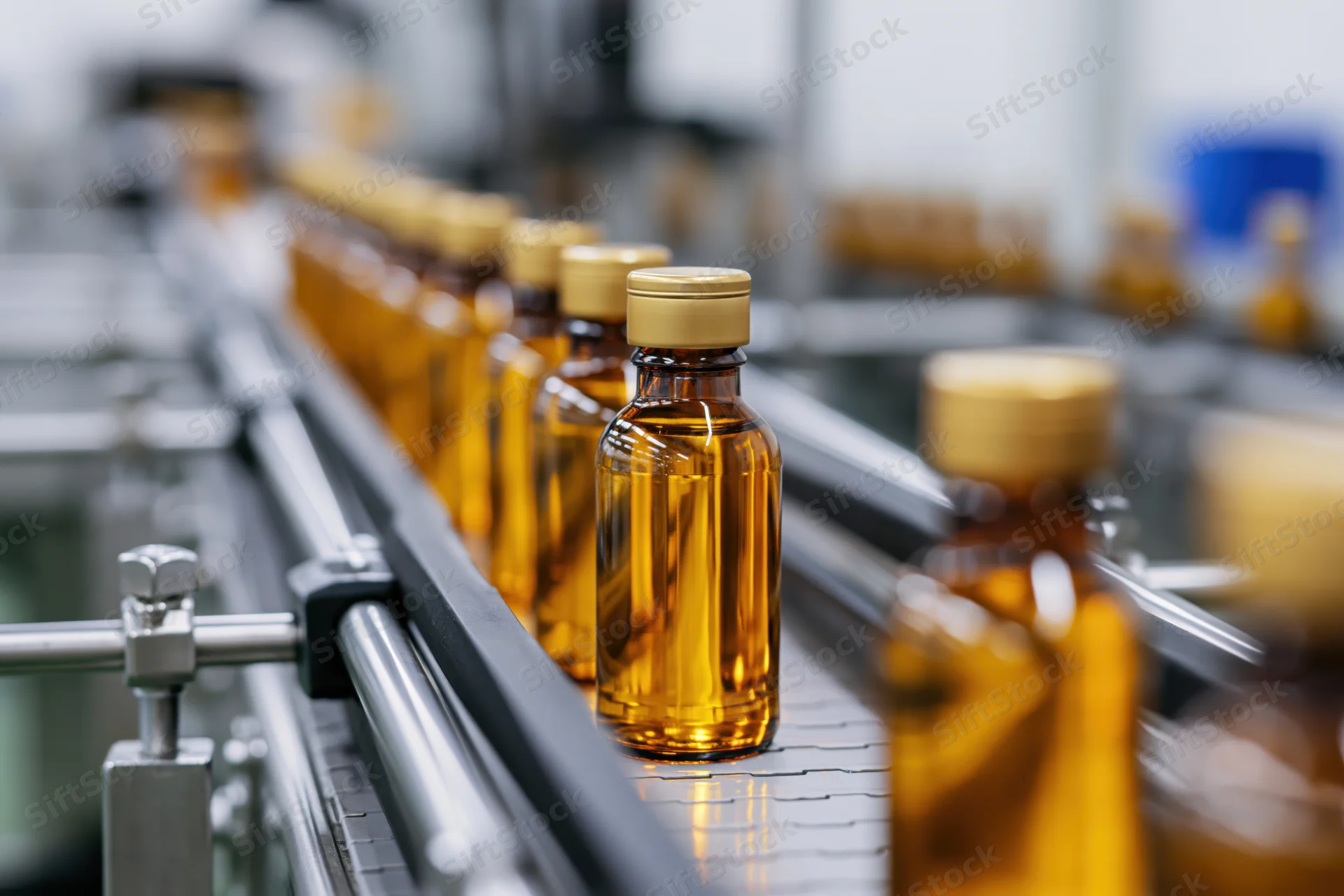 Amber glass bottles filled with golden liquid moving along a conveyor in a factory