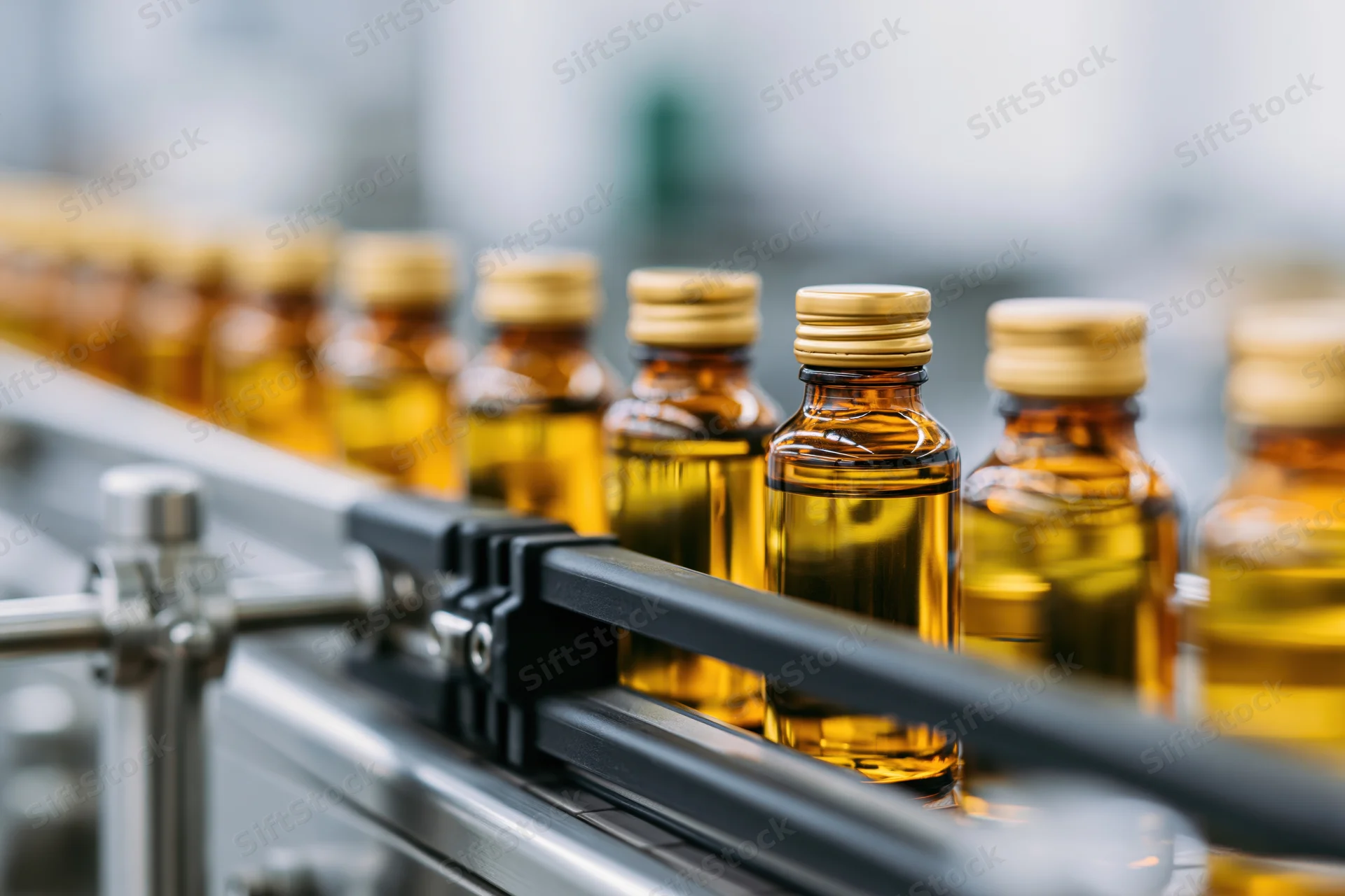 Amber glass bottles filled with golden liquid moving along a conveyor belt in a factory
