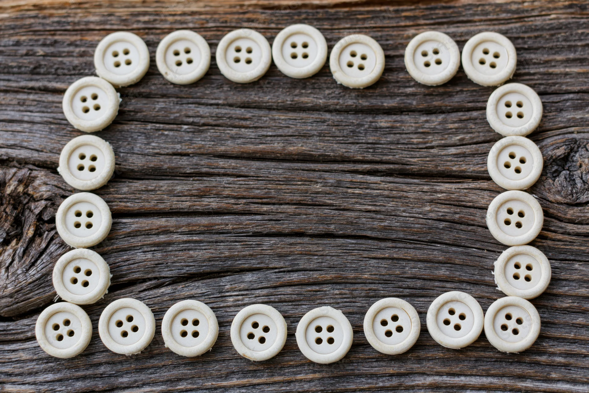 Cream buttons arranged in a rectangular frame on a weathered wooden surface